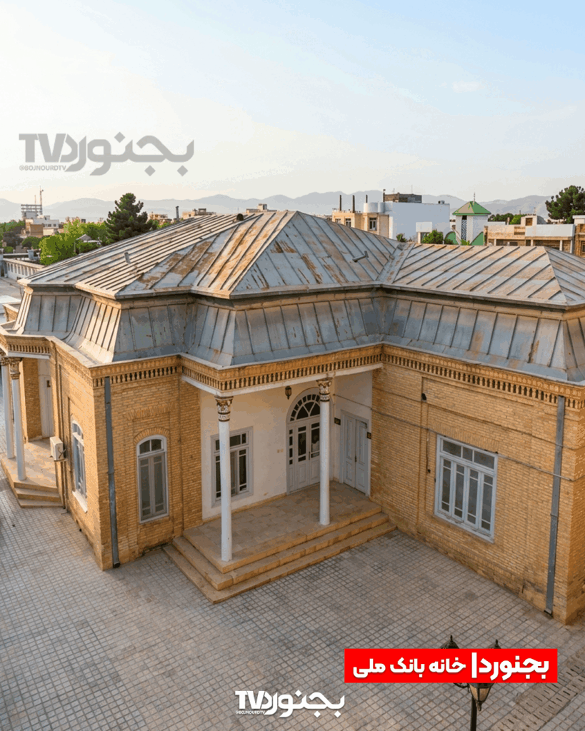 نمای هوایی خانه بانک ملی بجنورد با معماری آجری، سقف شیروانی فلزی و ستون‌های سفید در بافت شهری